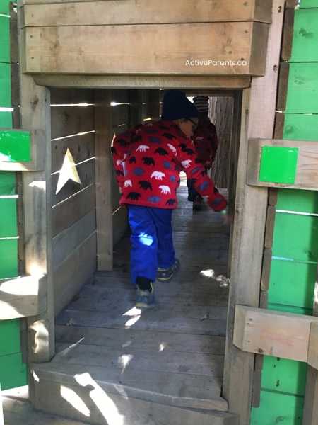 child in red coat exploring the tree walk village at Treetop Trekking Hamilton