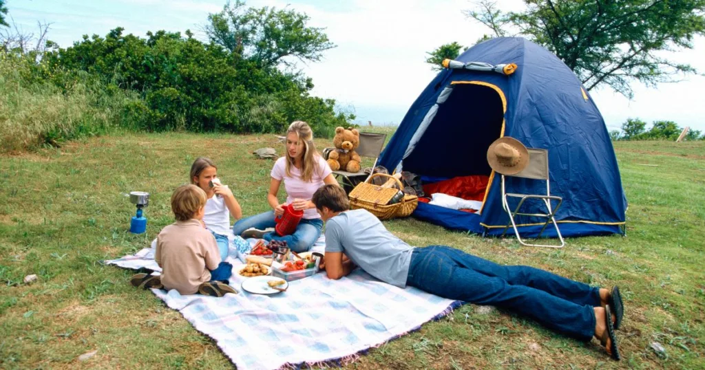 famiyl sitting in front of their tent camping in ontario