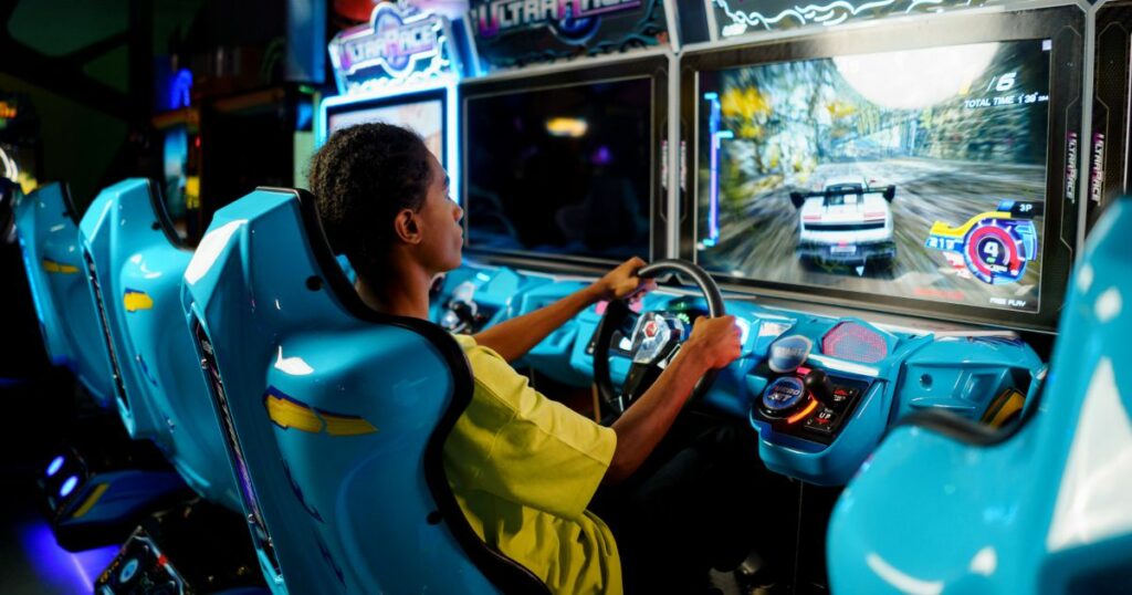 teenage boy playing a driving video game at the arcade
